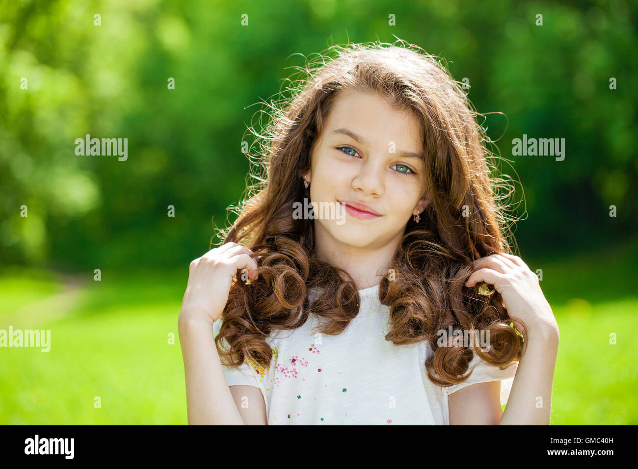Ritratto di una giovane e bella bambina sullo sfondo del parco di estate Foto Stock
