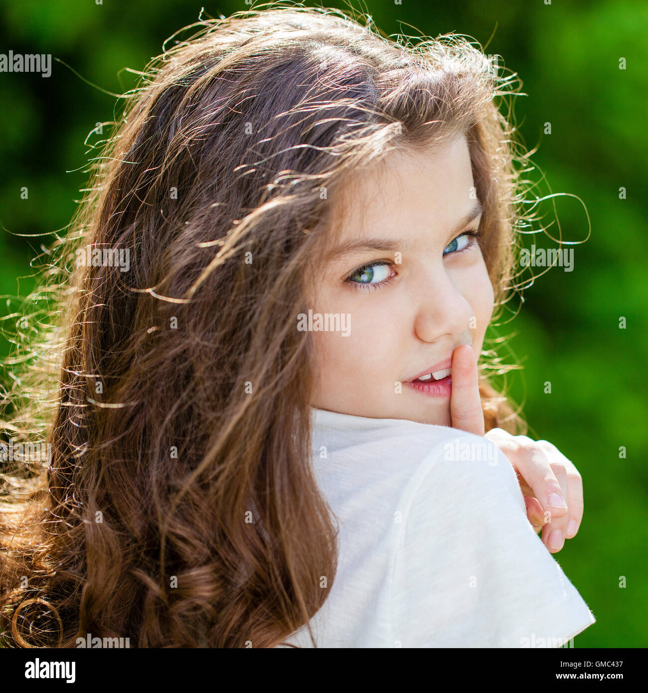 Giovane bella bambina ha messo l'indice per labbra come segno di silenzio, all'aperto estate Foto Stock