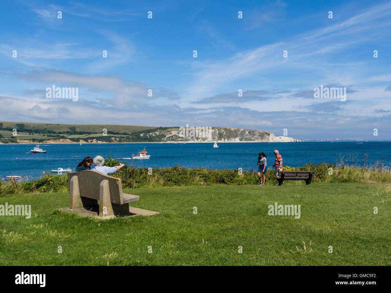 La gente seduta vicino: Peveril Point, Swanage, guardando attraverso la baia di Ballard Down, Regno Unito Foto Stock