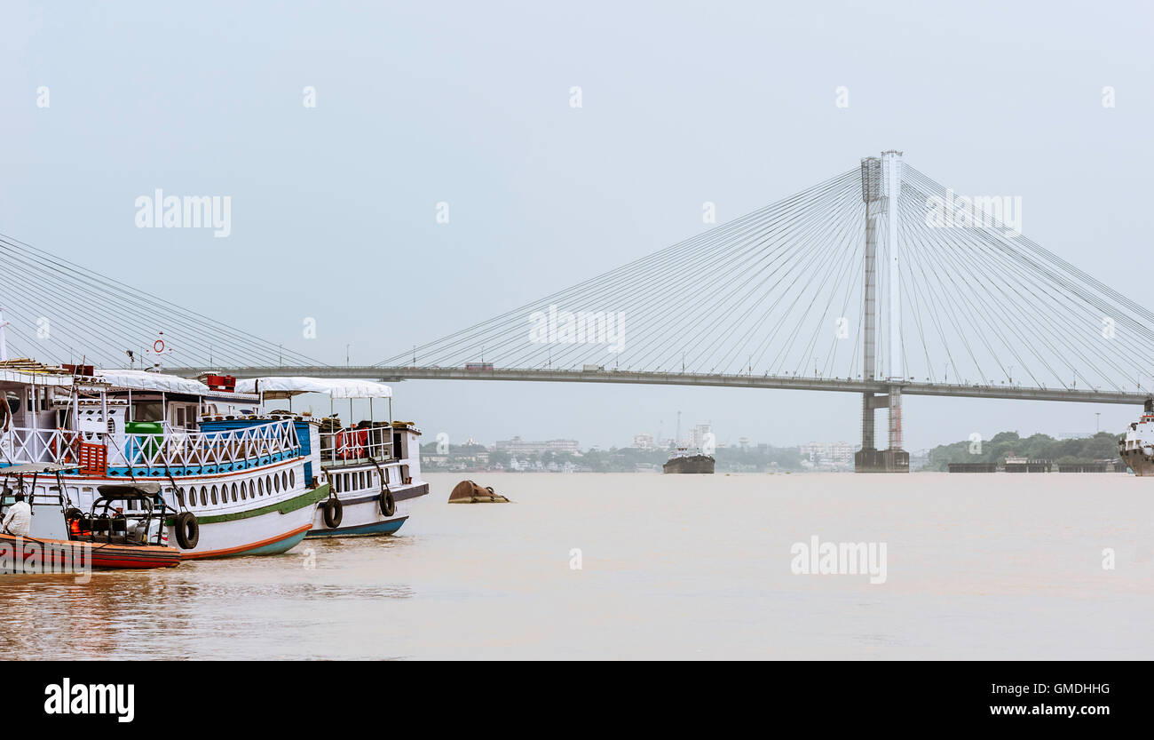 Il Fiume Hooghly all'alba con Imbarcazioni da fiume, navi e il Vidyasagar Setu ponte di sospensione come sfondo. Foto Stock