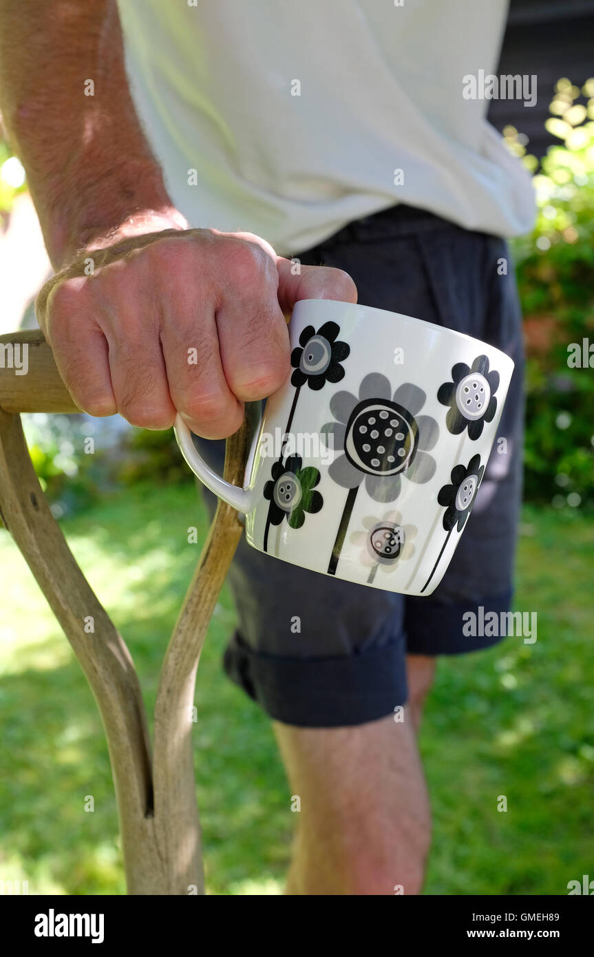 Maschio maturo giardiniere in appoggio le mani sulla parte superiore della forcella Foto Stock