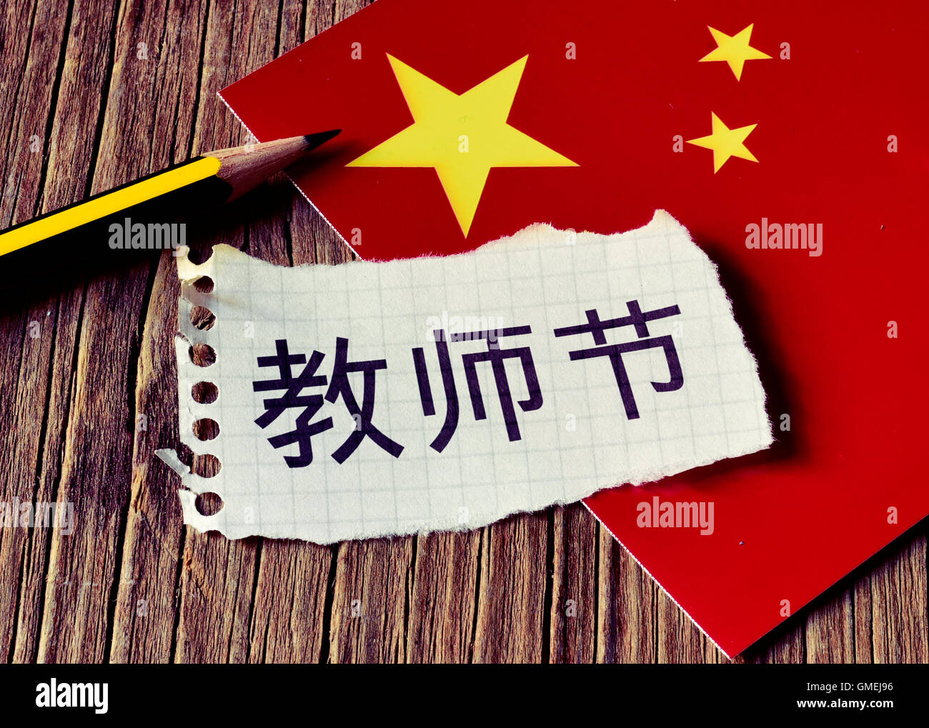 Primo piano di una pace della carta con il testo insegnanti giorno scritto in cinese, una matita e la bandiera della Cina, posto su un rustico wo Foto Stock