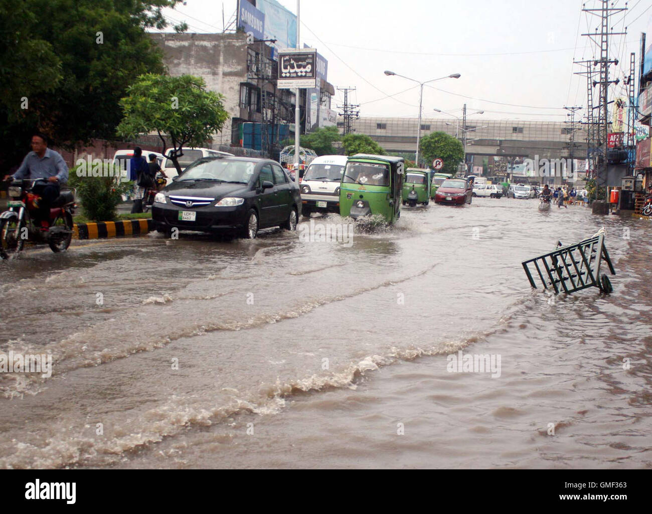 Pendolari passano attraverso il ristagno di acqua piovana su una strada durante la pioggia pesante della stagione dei monsoni di Lahore, giovedì 25 agosto, 2016. Le piogge torrenziali hanno colpito la capitale provinciale giovedì intasano le strade strade e provocare interruzioni di alimentazione. Almeno 136 alimentatori è scattato a causa della pioggia causando interruzioni di corrente in diverse zone della città. I più colpiti la zona era Jauhar città dove 64 mm di pioggia è stata registrata. Foto Stock