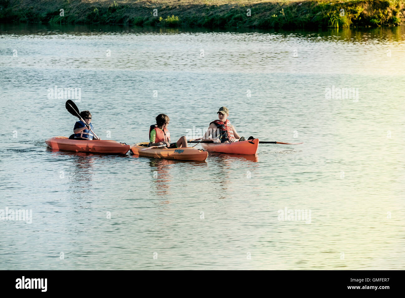 Tre caucasici ragazzi teen divertirsi in acqua in piccole noleggio kayak. A nord del fiume canadese, Oklahoma, Stati Uniti d'America. Foto Stock