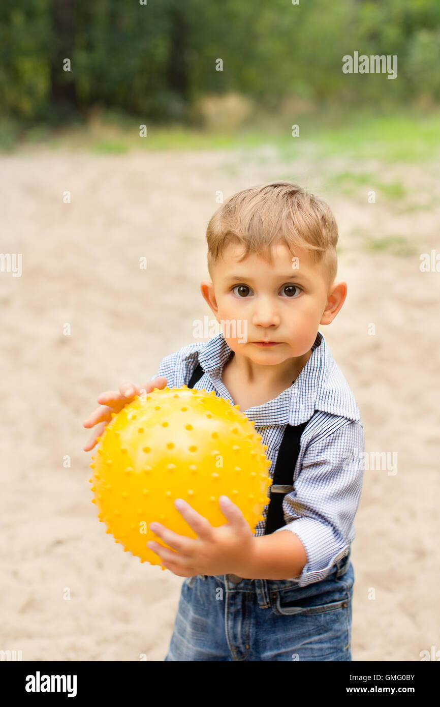 Ragazzo in possesso di una sfera di colore giallo nelle sue mani Foto Stock