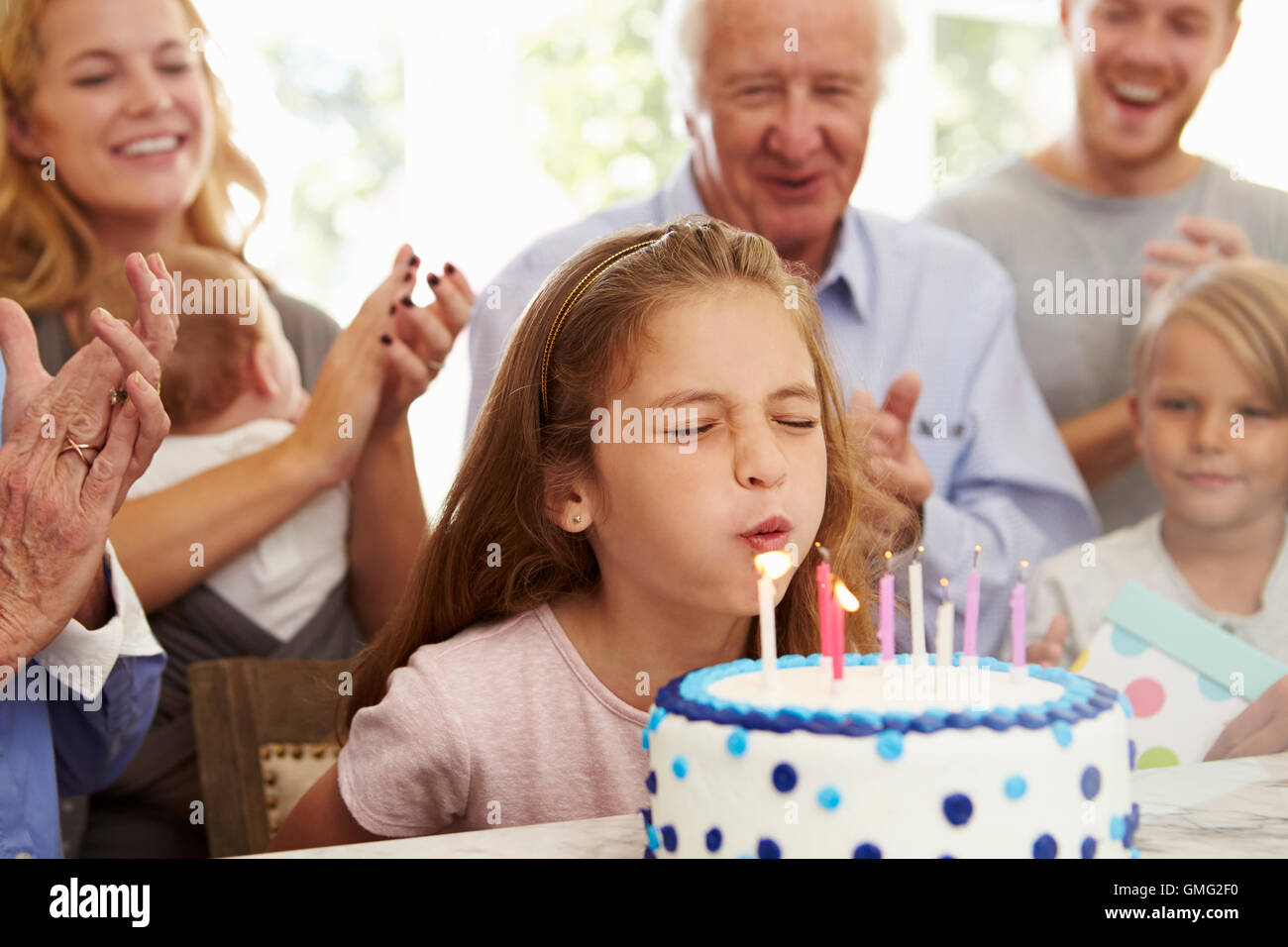 La ragazza si brucia la torta di compleanno candele alla festa di famiglia Foto Stock