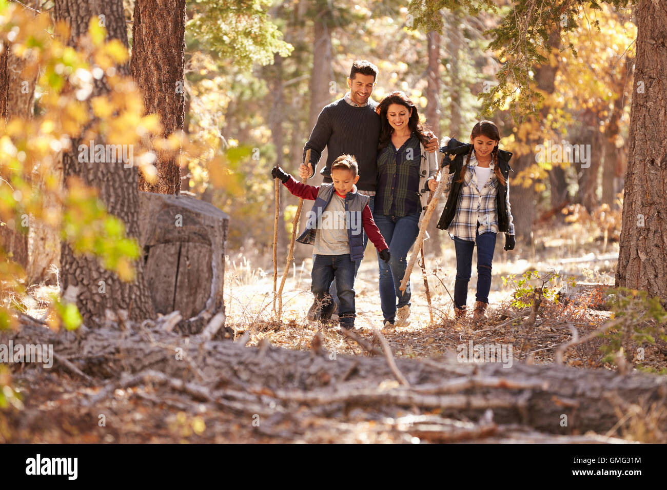 Felice famiglia ispanica con due bambini a camminare in una foresta Foto Stock