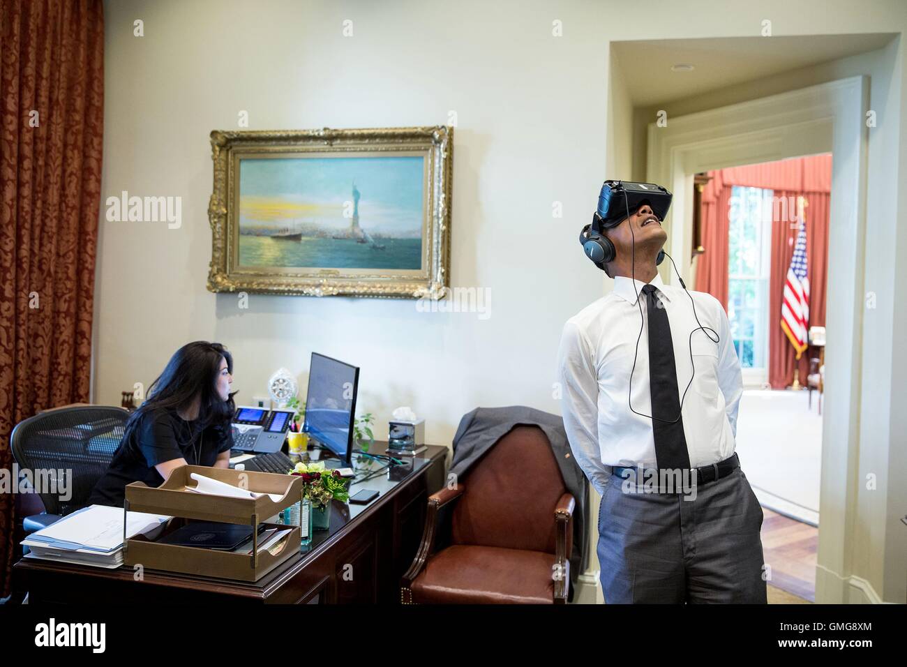 Il Presidente degli Stati Uniti Barack Obama orologi una realtà virtuale film catturati durante il suo viaggio verso il Parco Nazionale di Yosemite nel corso di quest'anno in esterno Ufficio Ovale della Casa Bianca Agosto 24, 2016 a Washington, DC. Personal aide Ferial Govashiri siede alla sua scrivania a sinistra. Foto Stock