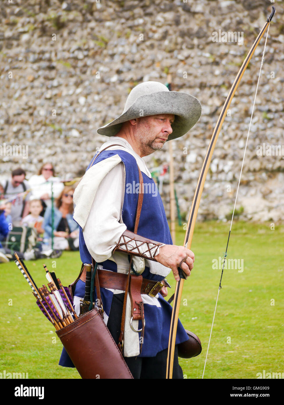 Un reenactor medievale visualizza longbow tecniche di tiro con l'arco all'interno del terreno di Portchester Castle, Inghilterra Foto Stock