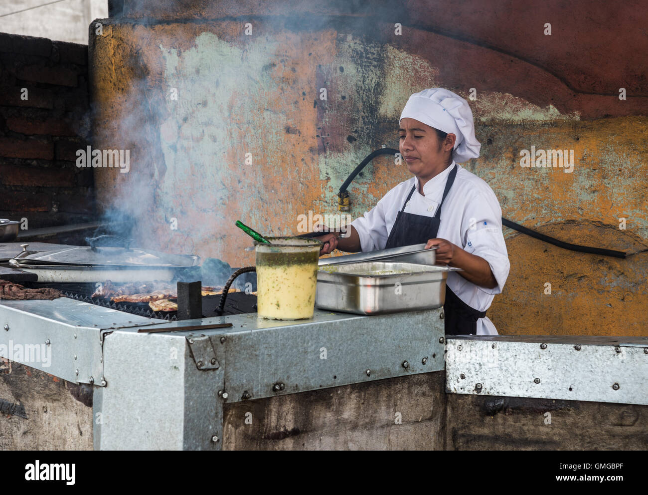 Una cuoca a cuocere la carne in una cucina aperta. Quito, Ecuador. Foto Stock