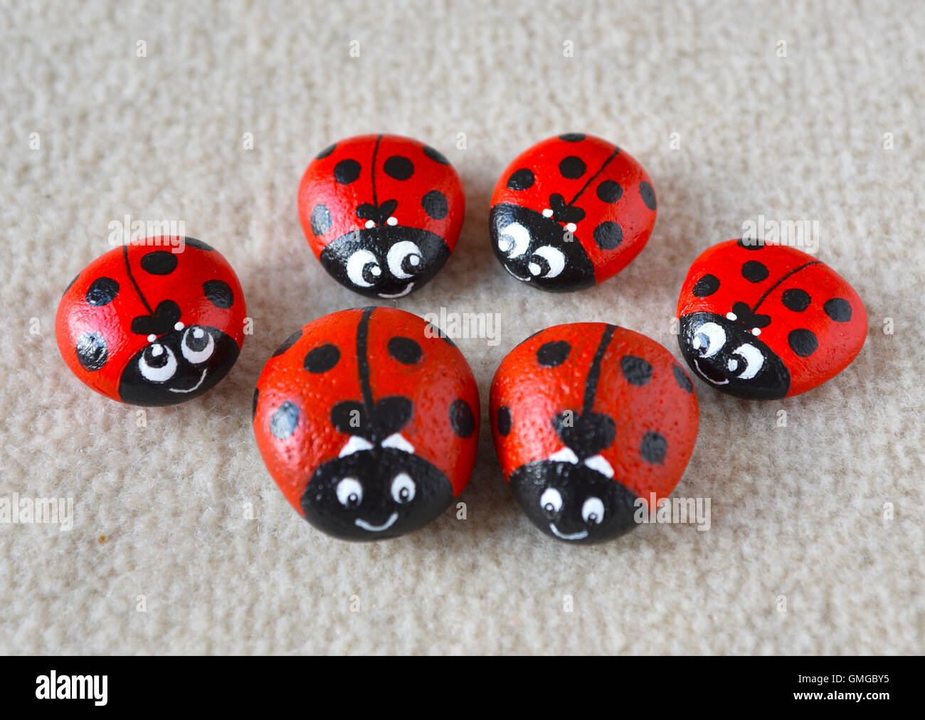 Ritratto di squisita la presentazione di 6 famiglia di coccinelle dipinte in colore rosso brillante con macchie nere sulla spiaggia di ciottoli. Foto Stock