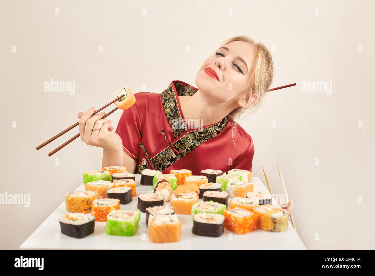 Ragazza sorridente in abito giapponese con sushi Foto stock - Alamy