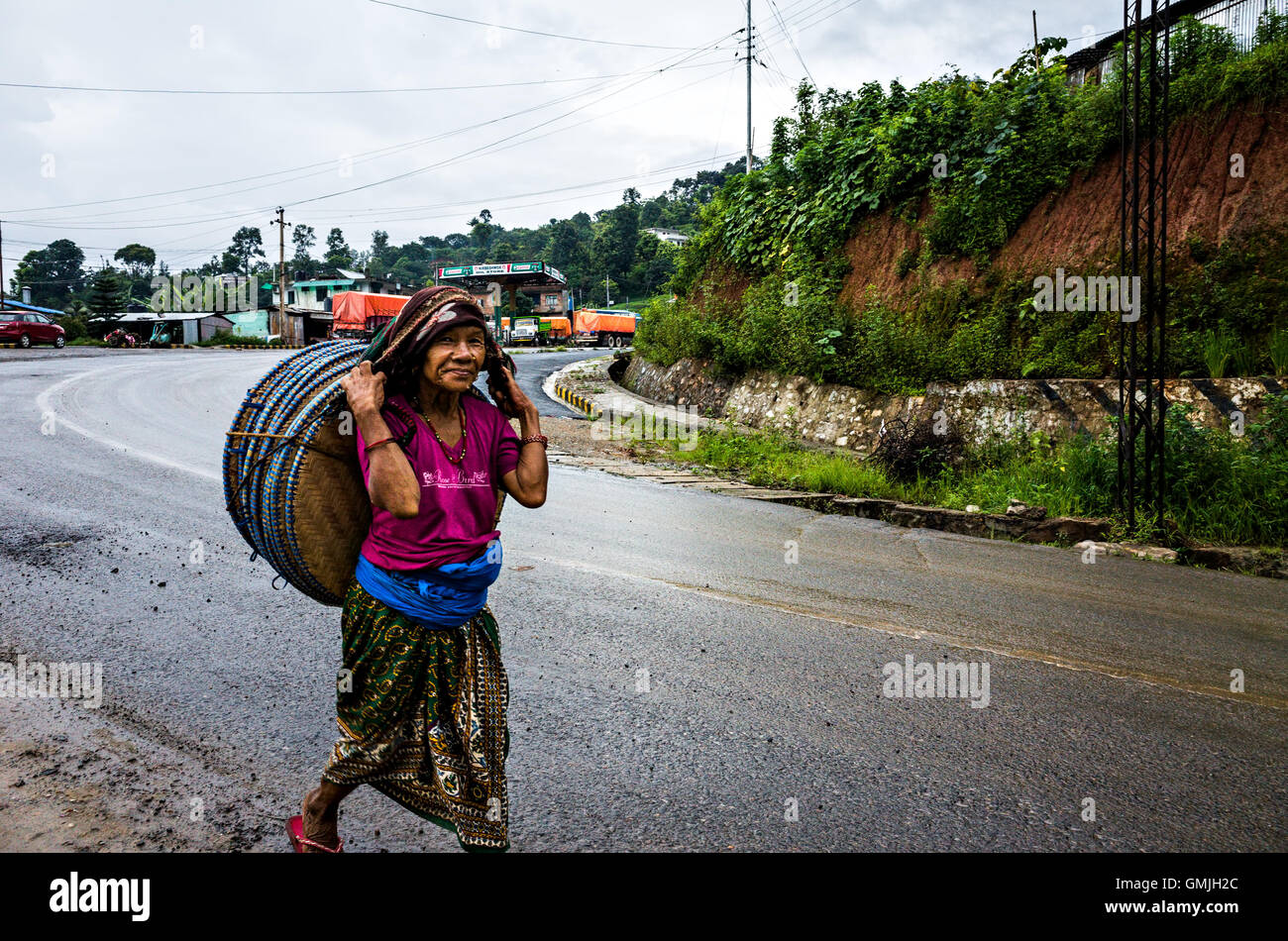 Una donna che cammina per vendere i suoi vassoi di bambù in Naubise vicino a Kathmandu, Nepal Foto Stock