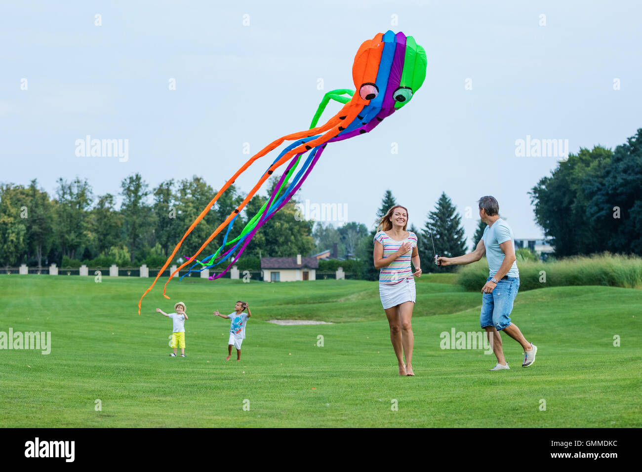 La famiglia felice aquilone volante insieme su un campo verde Foto Stock