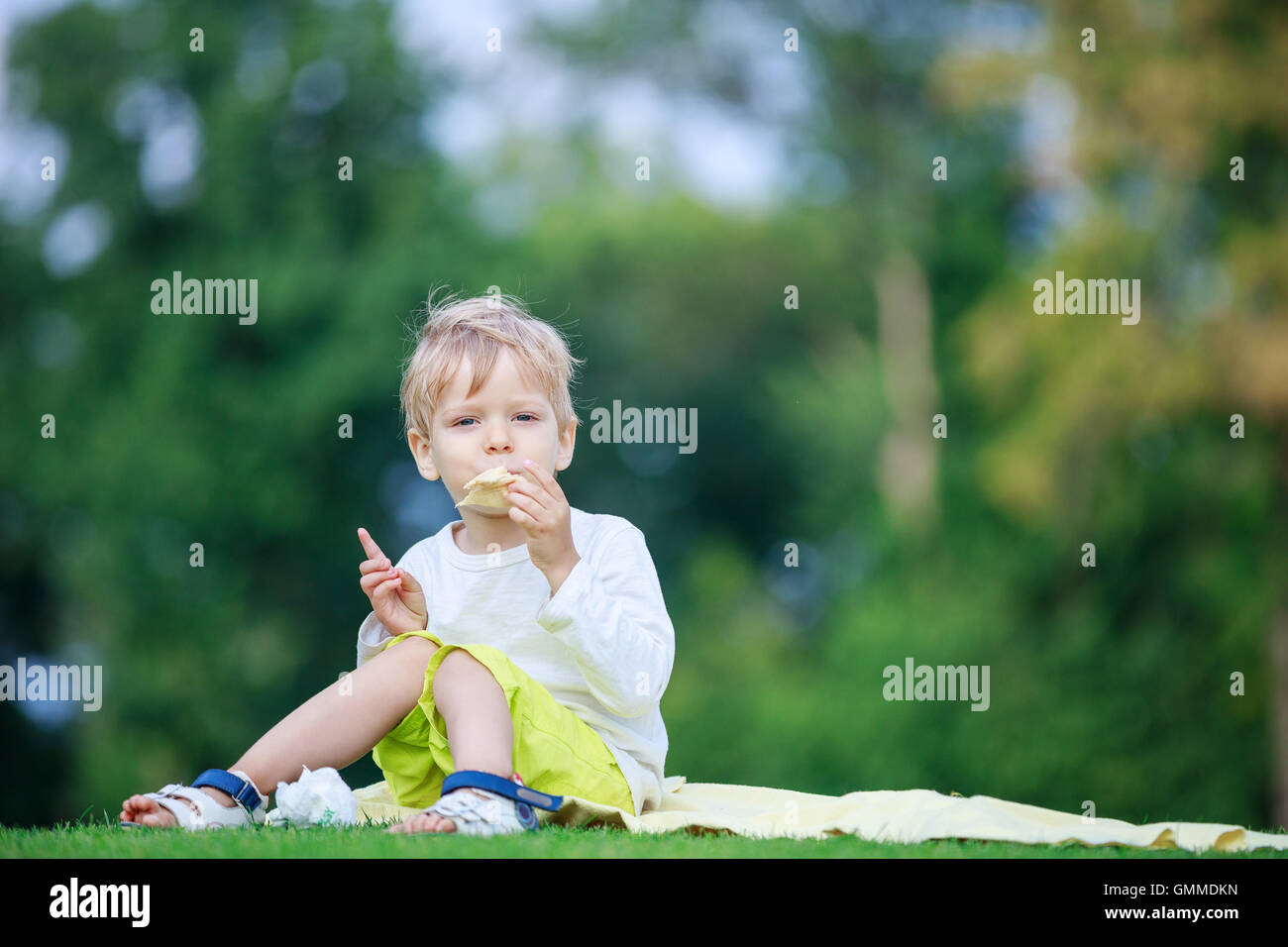 Carino il ragazzo biondo a mangiare il gelato in un parco Foto Stock