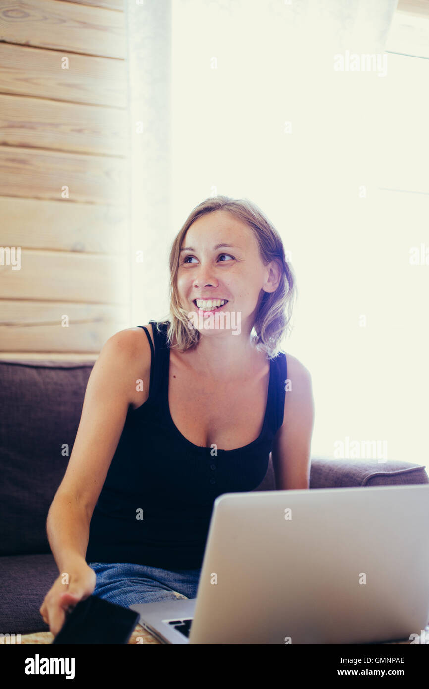 Donna sorridente con capelli corti a tavola laptop Foto Stock