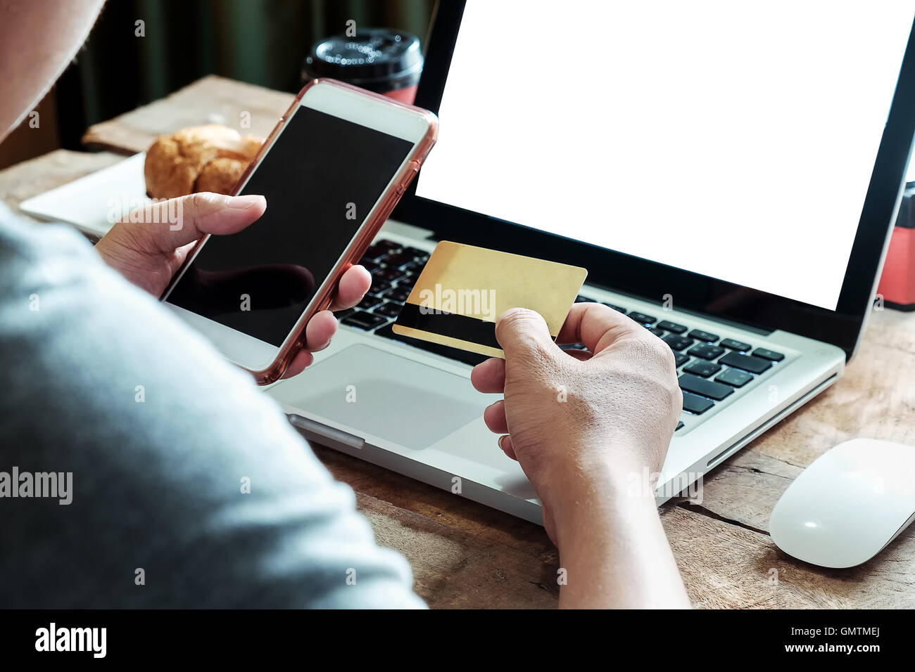 Man mano utilizzando lo smartphone e laptop holding carta di credito con i social media come lo shopping online concetto nella luce del mattino Foto Stock