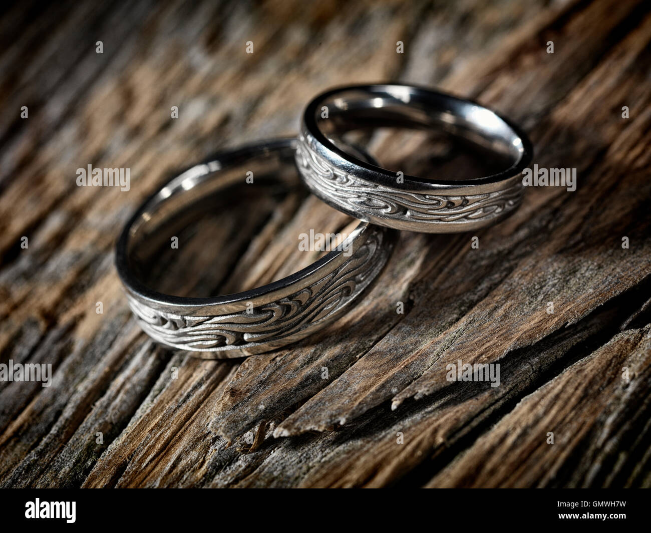 Due oro bianco anelli di nozze con Celtic design in legno rustico sfondo artistico, still life Foto Stock