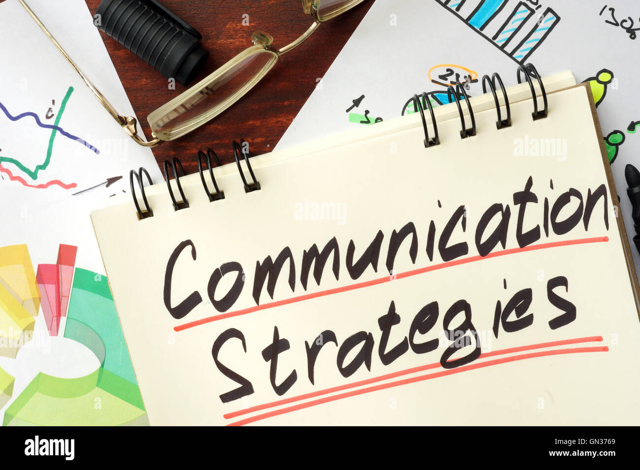 Blocco note con il segno nelle strategie di comunicazione su un sfondo di legno. Foto Stock