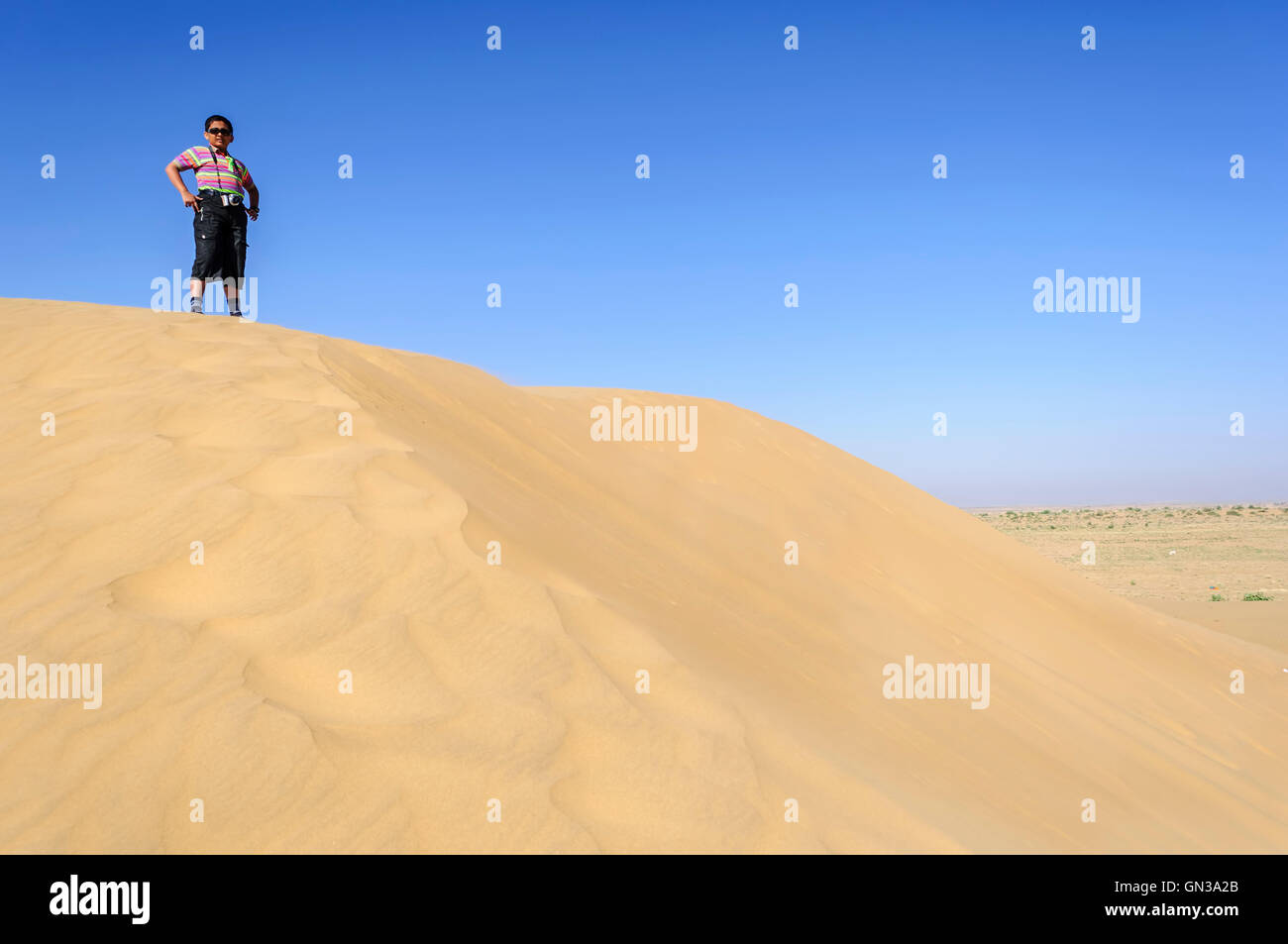 Ragazzo indiano, turistica, con il binocolo permanente sulla duna di sabbia del deserto del Parco Nazionale, Rajasthan, spazio di copia Foto Stock