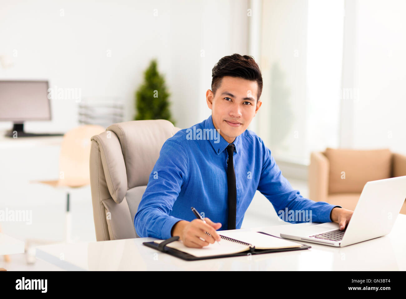 Sorridente giovane uomo d affari lavoro in ufficio Foto Stock