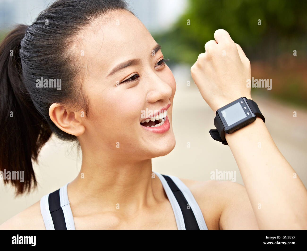 Giovane donna asiatica pareggiatore di rispondere o effettuare una chiamata utilizzando un orologio da polso dispositivo indossabile. Foto Stock