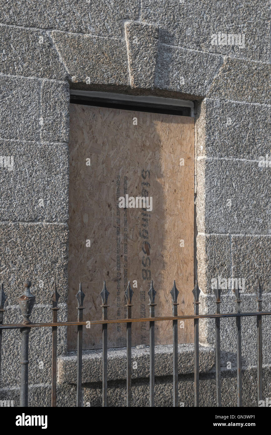 Finestra con persiane di vecchia costruzione in pietra, con ringhiere in ferro visibili. Come metafora per il concetto di accesso negato, o barriera. Foto Stock