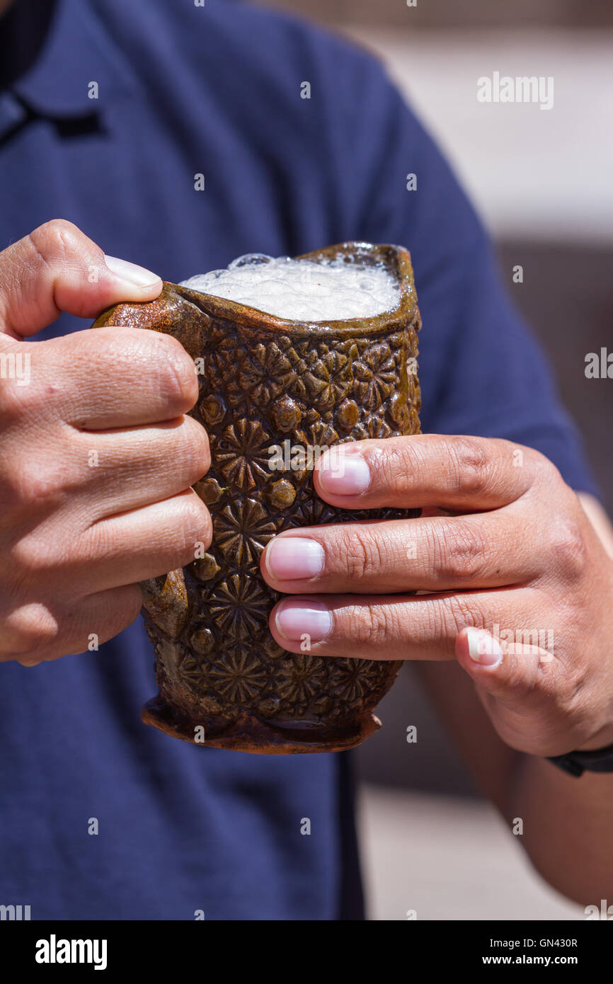 Close up di un adulto di sesso maschile mani coppa di ritegno con bianca peruviana Chicha Foto Stock