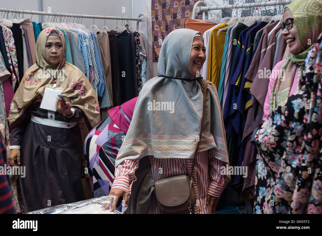 Due donne sorriso reciprocamente in corrispondenza di un supporto durante la musulmana festival di moda Hijabfest in Makassar, Indonesia, l'8 aprile 2016. Foto Stock