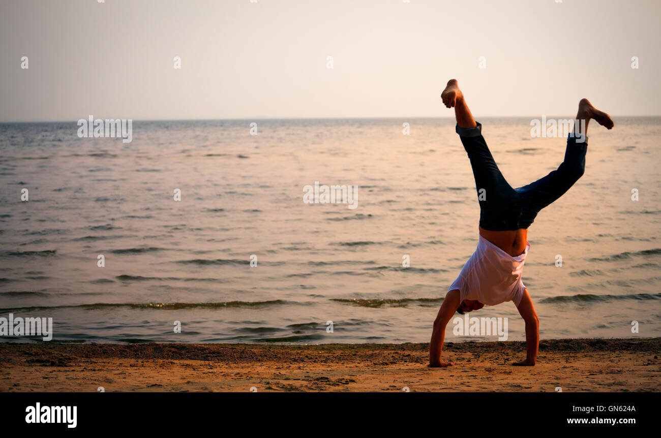 L'uomo facendo handstand sulla spiaggia Foto Stock