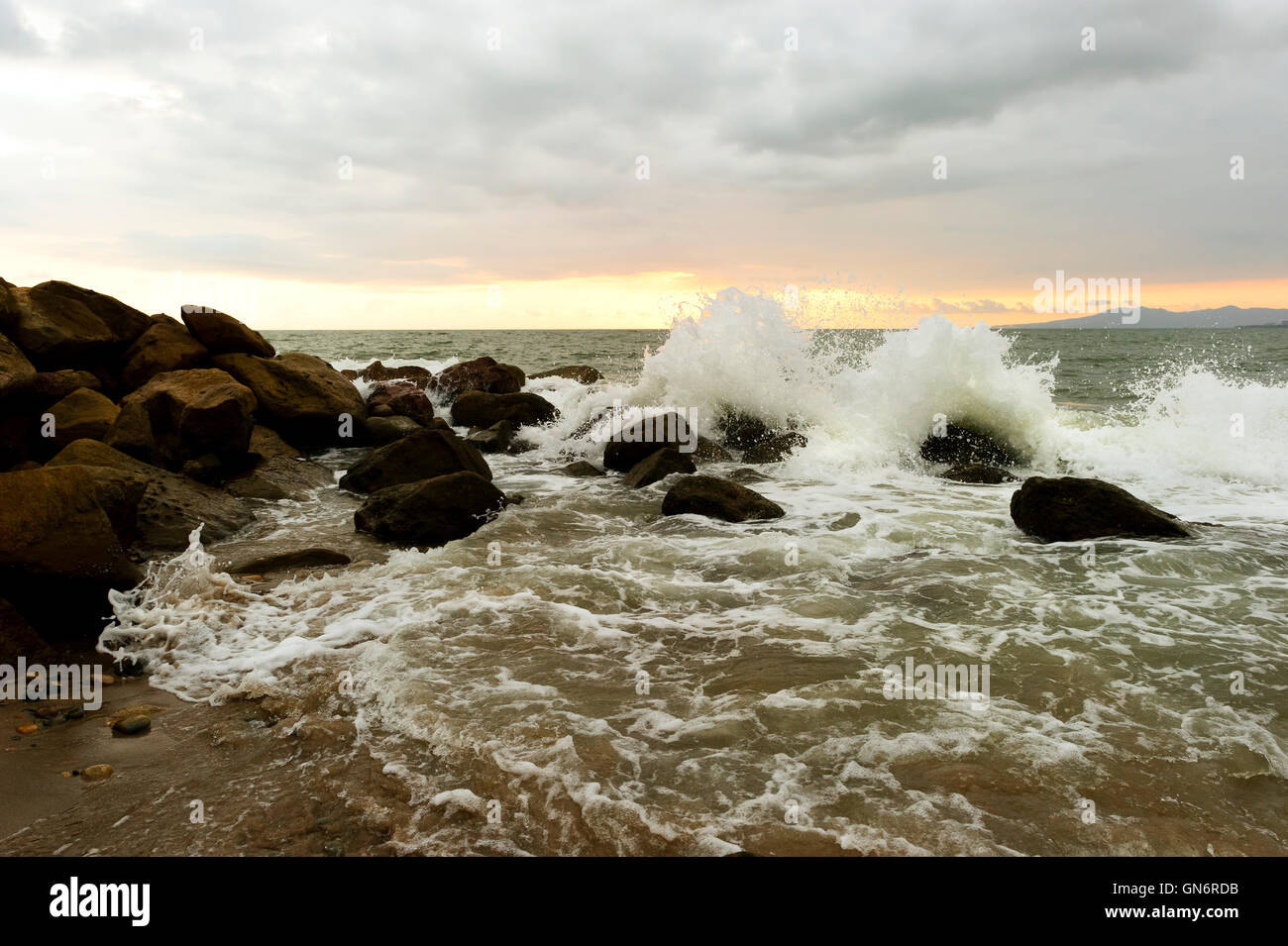 Onde si infrangono è un oceano onda correndo a riva di colpire il mare di rocce e sparare in aria come ocean spray. Foto Stock