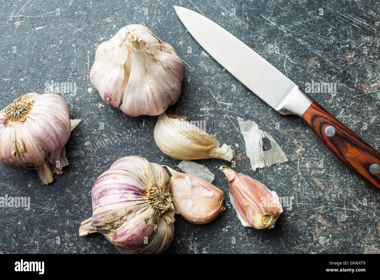 L'aglio fresco con il coltello sul tavolo da cucina. Foto Stock