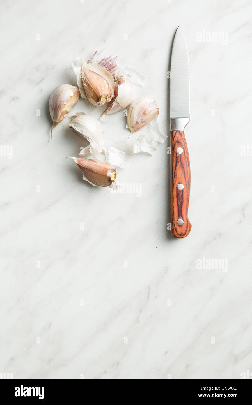L'aglio fresco con il coltello sul tavolo da cucina. Foto Stock