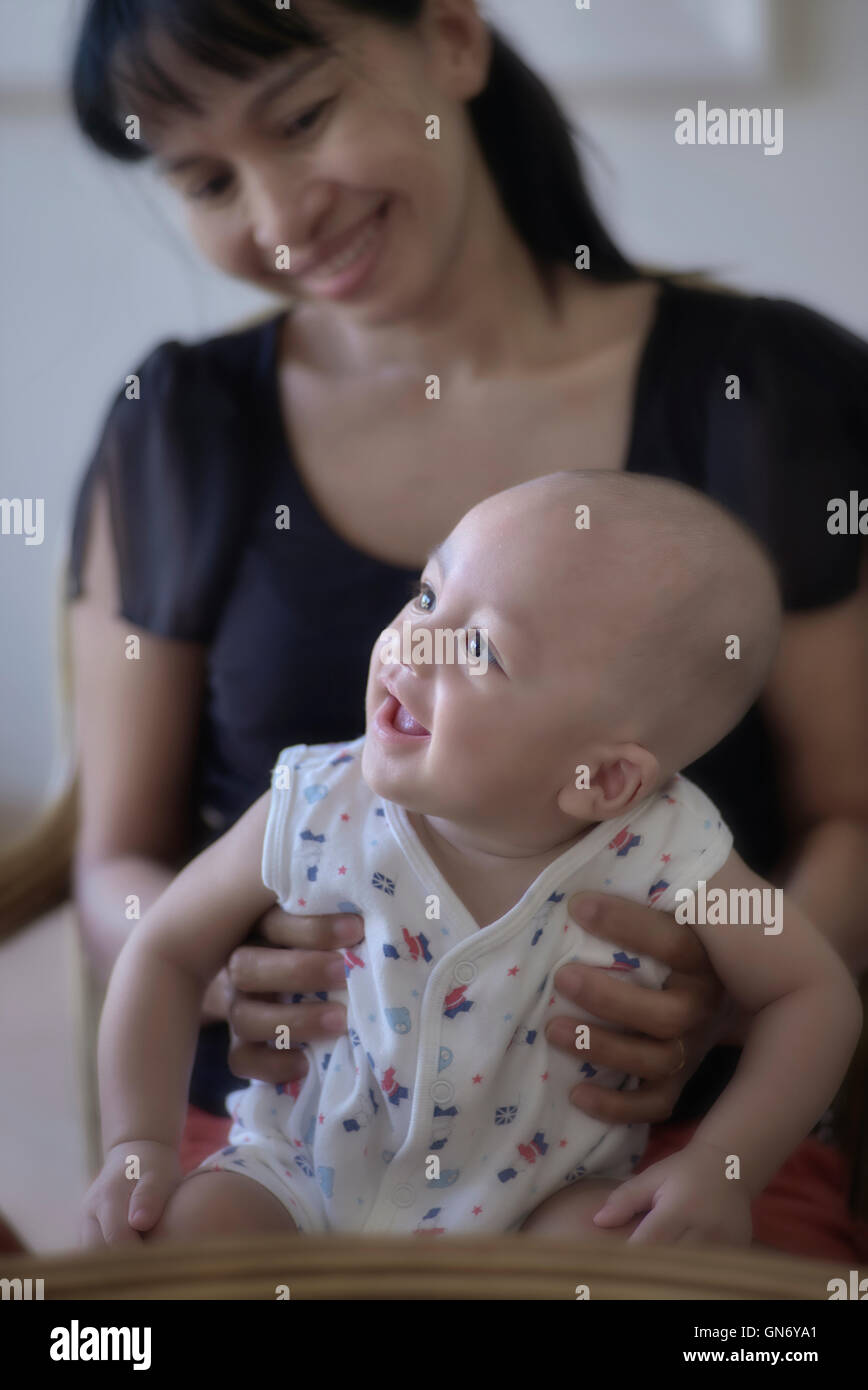 Asian madre e suo Thai/Inglese razza mista bambino di 6 mesi. Thailandia SUDEST ASIATICO Foto Stock