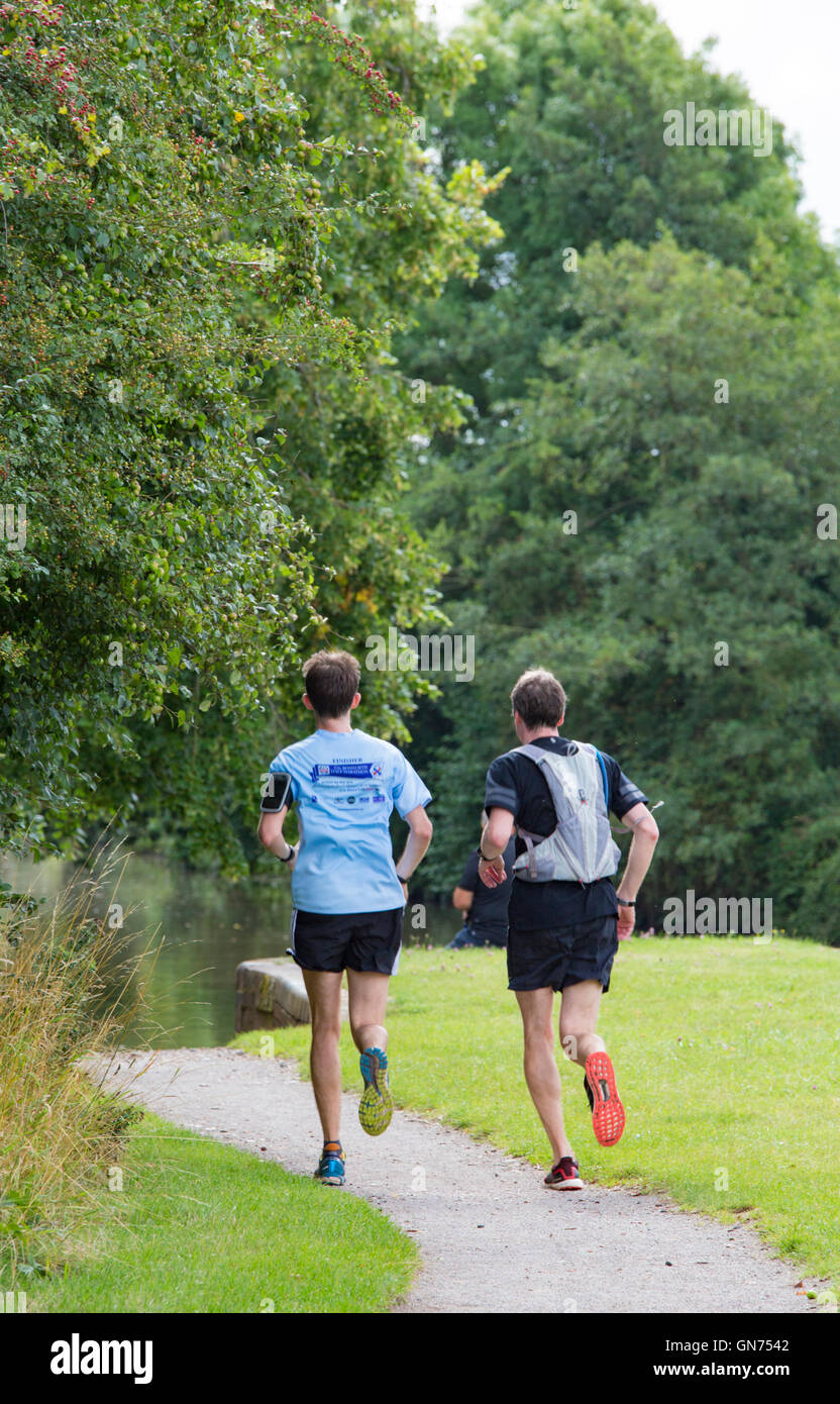 Due maschi in esecuzione su un canale alzaia, England, Regno Unito Foto Stock