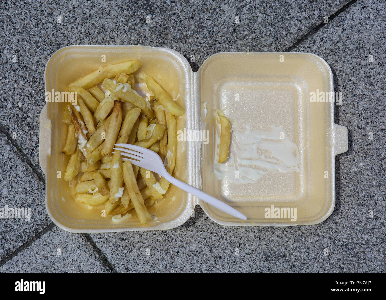 Una plastica scartato il fast food vassoio contenente alcuni chip e una forcella di plastica Foto Stock