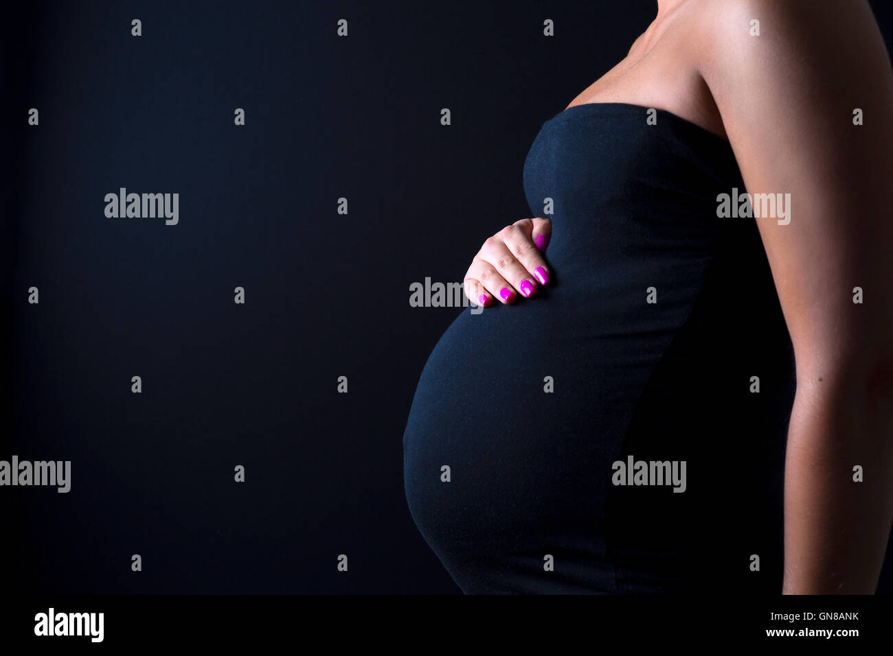 Giovane donna in stato di gravidanza sta con le mani in corrispondenza del ventre Foto Stock