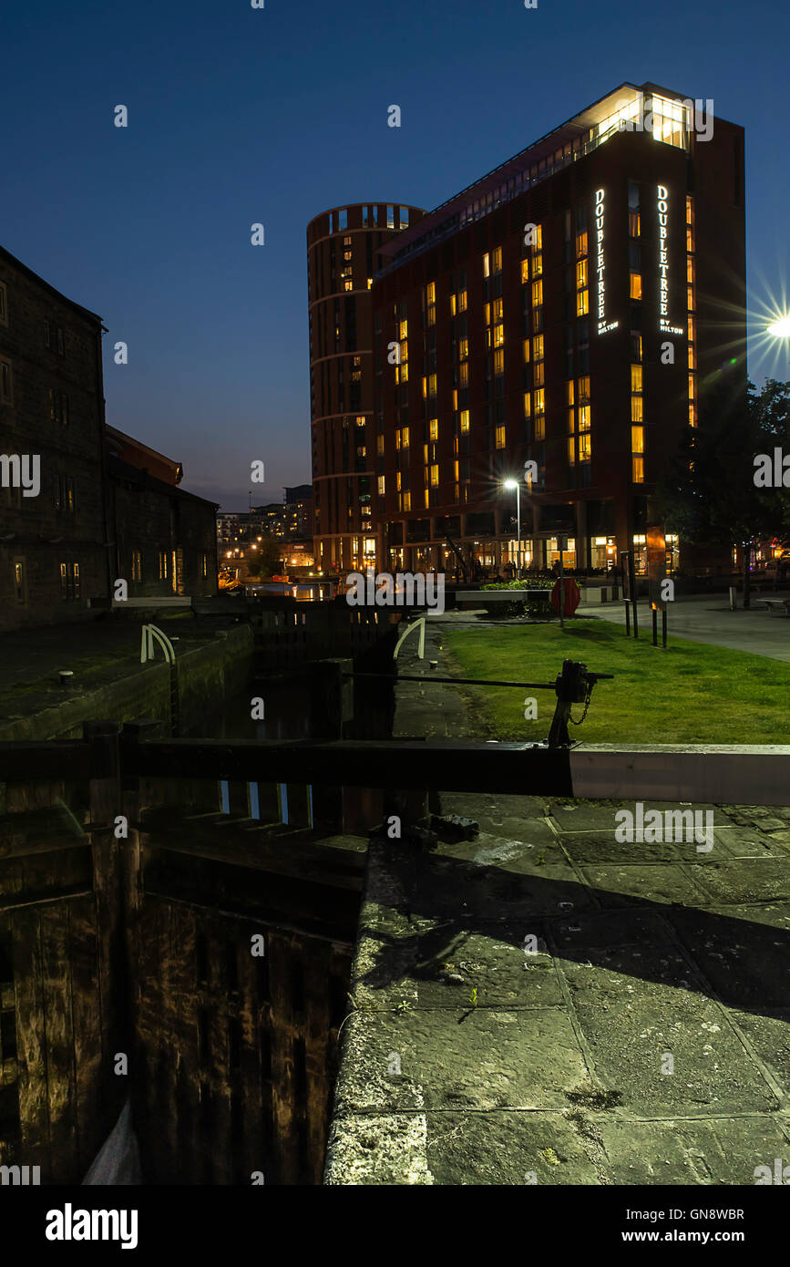 In tarda serata la vista dell'illuminato Double Tree by Hilton Hotel e Canal cancelli di blocco a Granary Wharf, Leeds, Regno Unito. Foto Stock