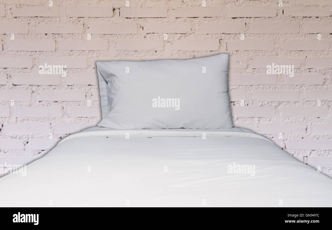 Un letto singolo con il bianco muro di mattoni decorata in coffee shop Foto Stock