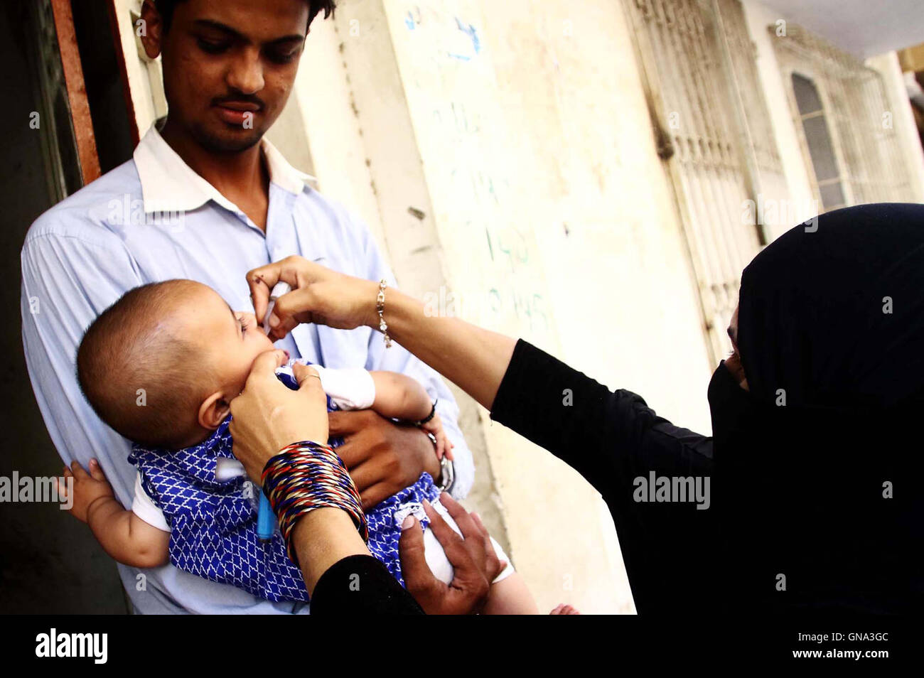 Anti virus polio i diruttori somministrare il vaccino al bambino, nell area di Mehmoodabad di Karachi Lunedì 29 Agosto, 2016. Foto Stock