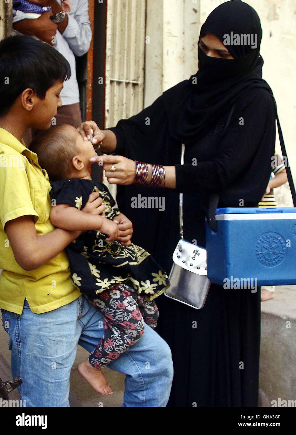 Anti virus polio i diruttori somministrare il vaccino al bambino, nell area di Mehmoodabad di Karachi Lunedì 29 Agosto, 2016. Foto Stock