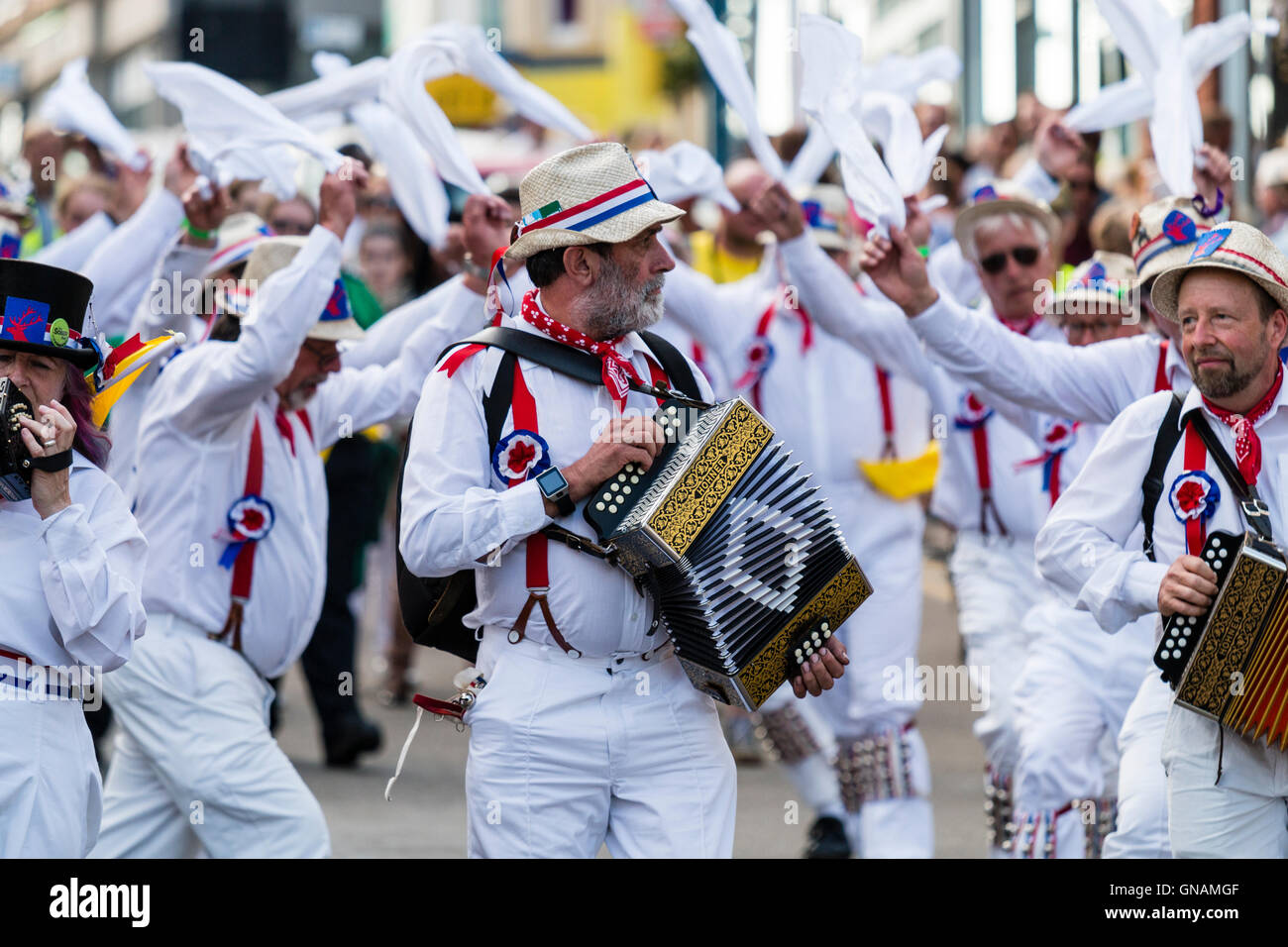 Tre morris fisarmonica giocatori che portano Hartley Morris lato come ballano sventolando hankies bianco durante una parata in città street. Venendo verso il visualizzatore. Foto Stock