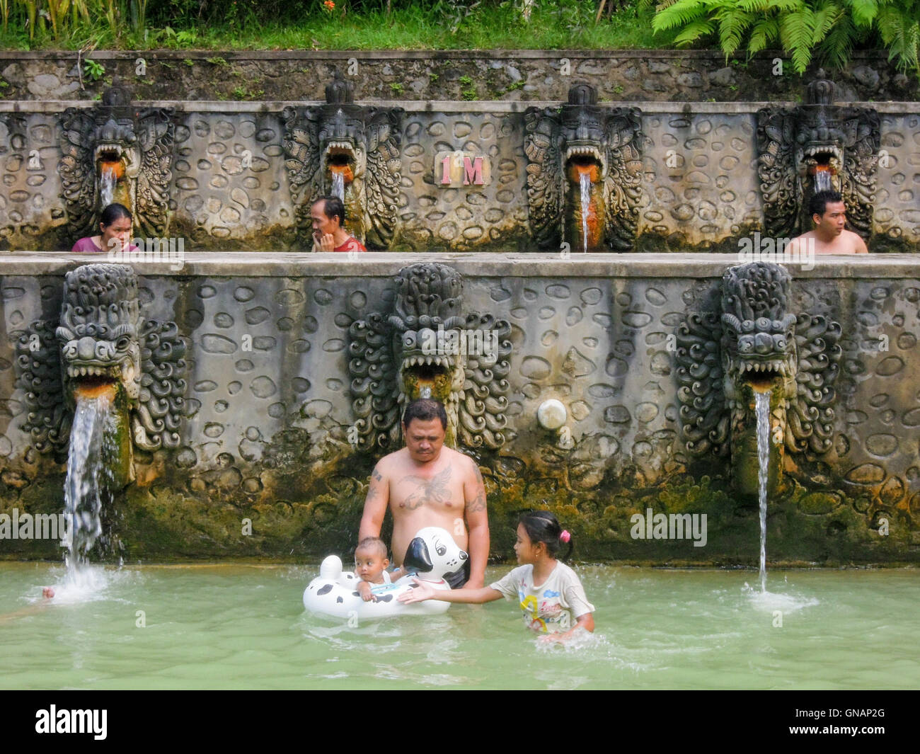 Banjar (Bali), Indonesia - 8 febbraio 2013: Le persone sotto i getti di acqua di piscina pubblica a Banjar sull'isola di Bali, Indo Foto Stock