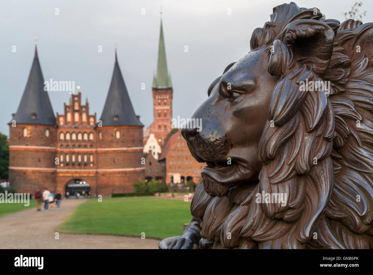 Lion statua che si trova nella parte anteriore della porta della città Holstentor e Chiesa di San Pietro, Lubecca, Schleswig-Holstein, Germania Foto Stock