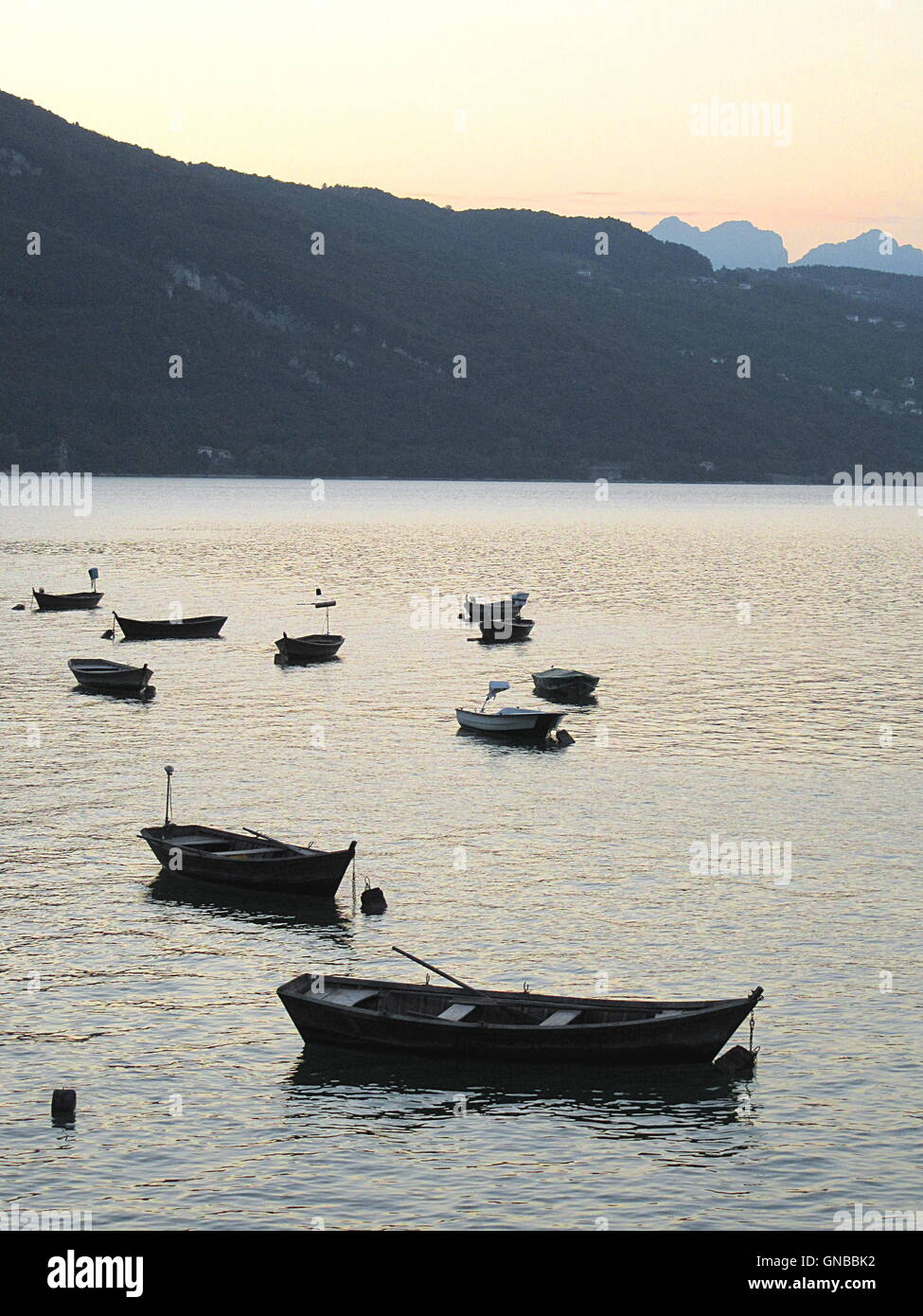 Full frame shot del tramonto con vuoto barche di legno sul lago di montagna e le montagne sullo sfondo Foto Stock