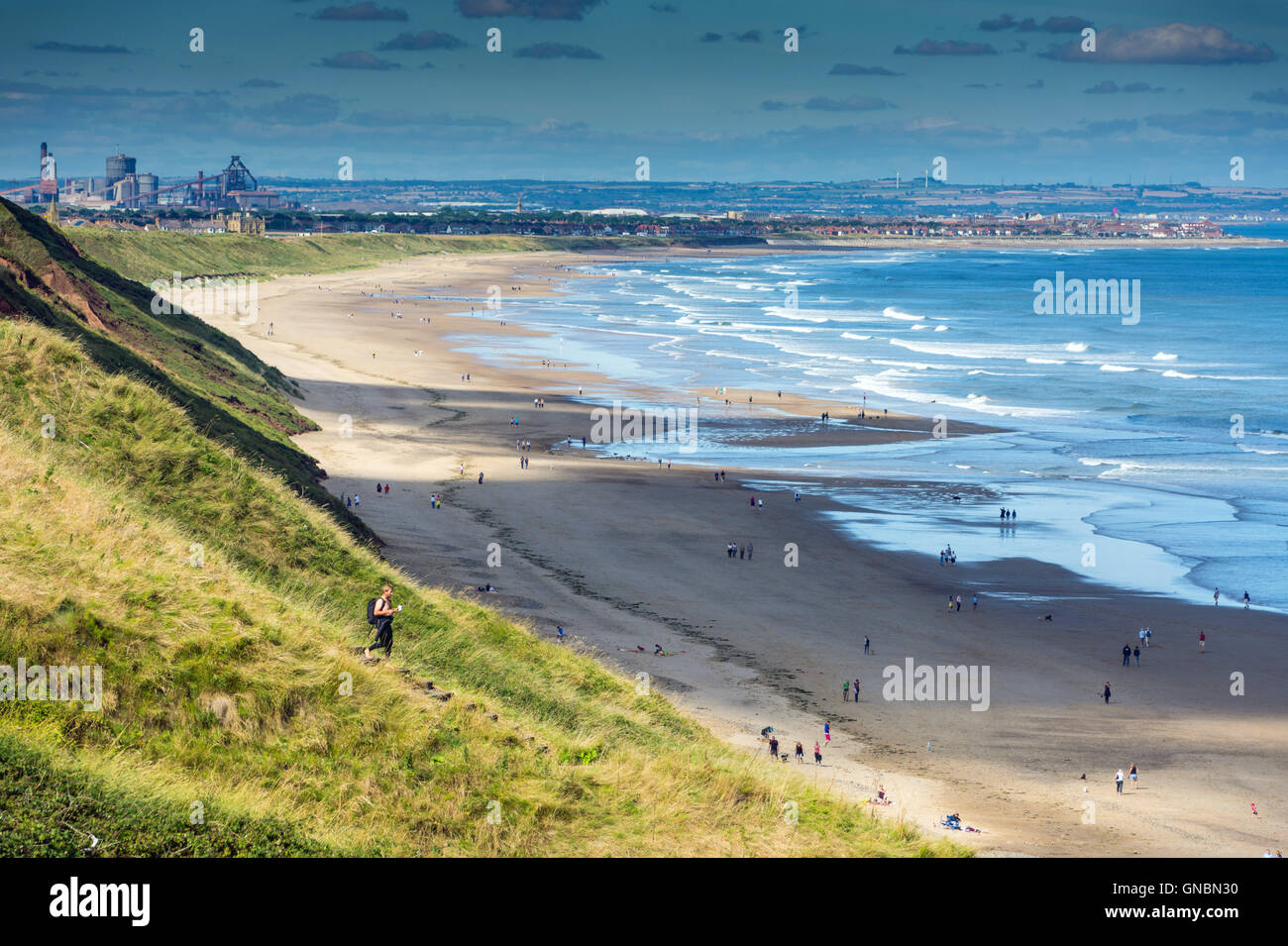 Spiaggia di sabbia, onde da surf e distante Redcar steel works, Saltburn, in riva al mare Foto Stock