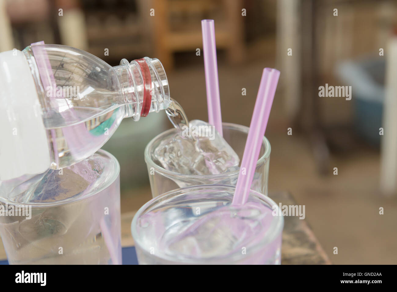 Colata di acqua su un vetro liscio con ghiaccio e rosa paglia. Messa a fuoco selettiva. Foto Stock