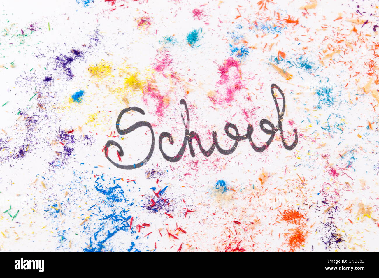 Scuola di parola scritta sul libro bianco coperto di matite colorate leftover di affilatura Foto Stock