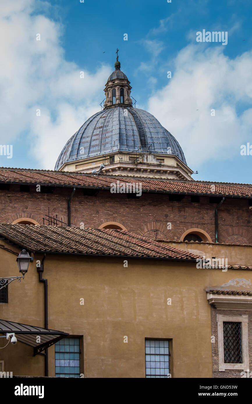 Tipico colore arancio edificio di Roma. Dietro una cupola di una chiesa. Cielo nuvoloso. Foto Stock