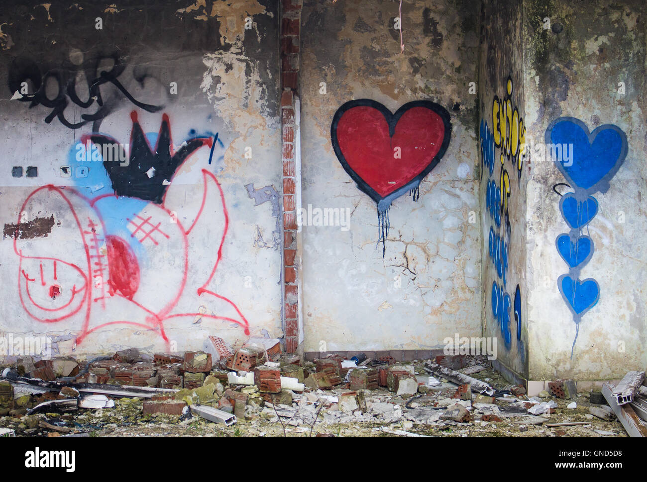 Il rosso e il blu cuori graffiti dipinto sul muro di un edificio abbandonato. Foto Stock